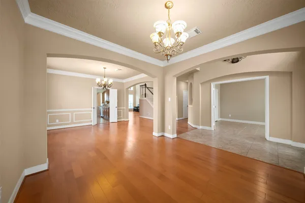 a view of a room with wooden floor chandelier and windows