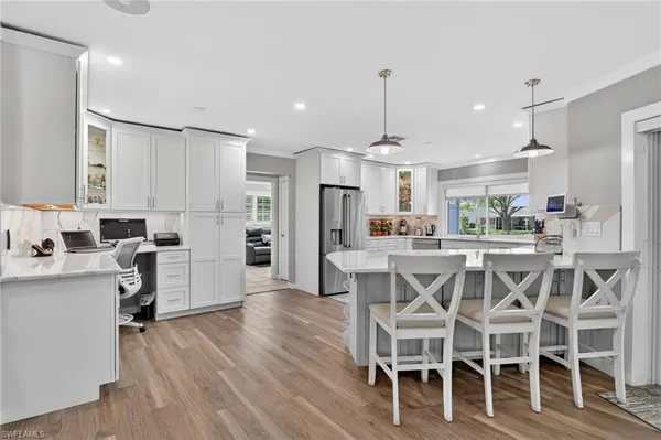 a kitchen with a dining table chairs wooden floor cabinets and stainless steel appliances