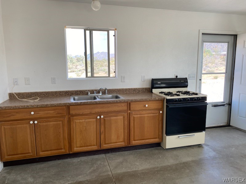 11135 Bennie Road Yucca, AZ 86438 - Photo 11 of 27 a kitchen with granite countertop a stove a sink and a microwave