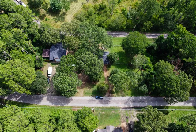 an aerial view of a houses with a yard and lake