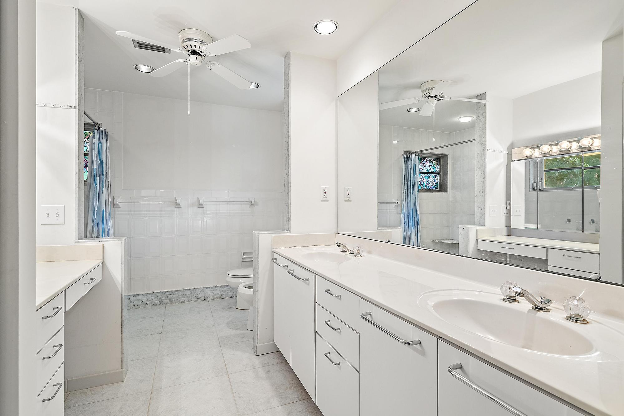 16486 95th Avenue North Jupiter, FL 33478 - Photo 13 of 34 a spacious bathroom with a double vanity sink toilet mirror and bathtub