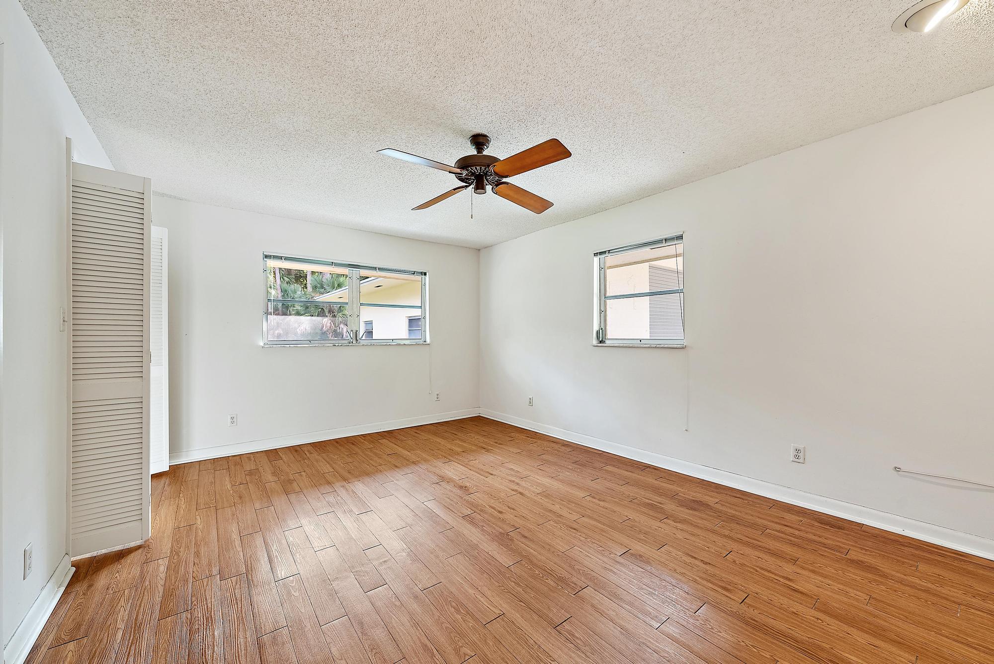 16486 95th Avenue North Jupiter, FL 33478 - Photo 18 of 34 an empty room with wooden floor and windows