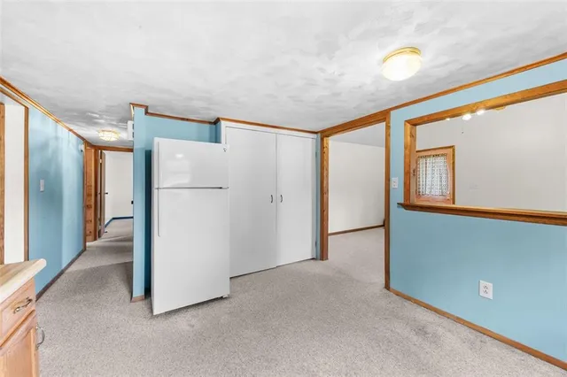a view of a refrigerator in kitchen and an empty room