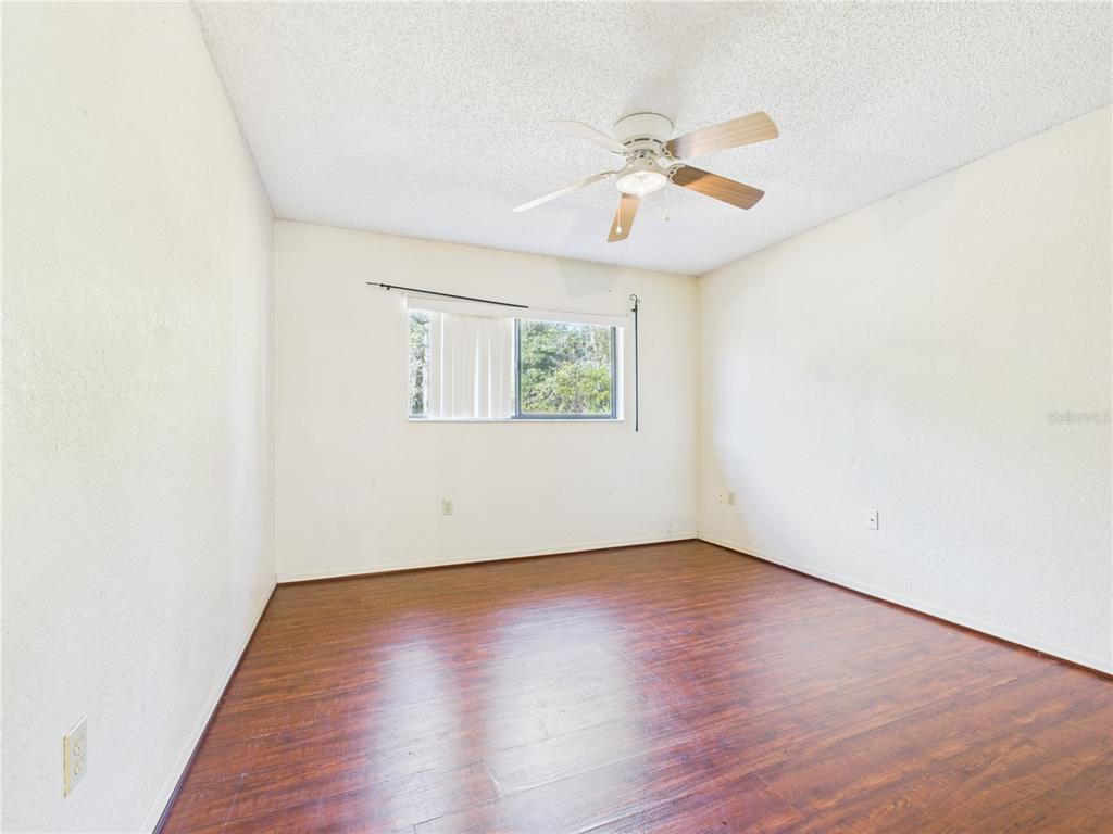 4116 Jason Road Spring Hill, FL 34608 - Photo 18 of 66 an empty room with wooden floor fan and windows