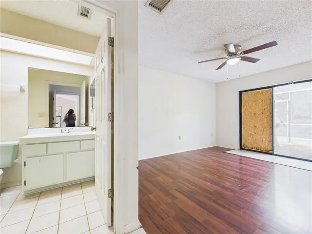 an empty room with wooden floor ceiling fan and windows