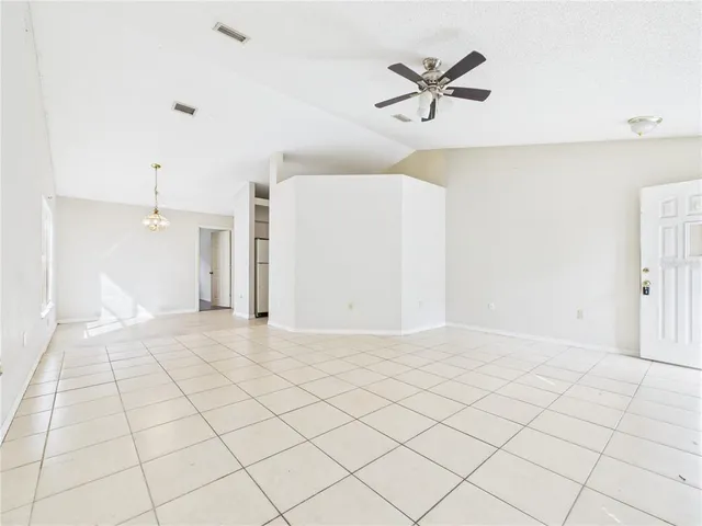 an empty room with wooden floor ceiling fan and windows