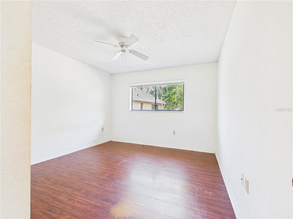 4116 Jason Road Spring Hill, FL 34608 - Photo 6 of 66 an empty room with wooden floor ceiling fan and windows
