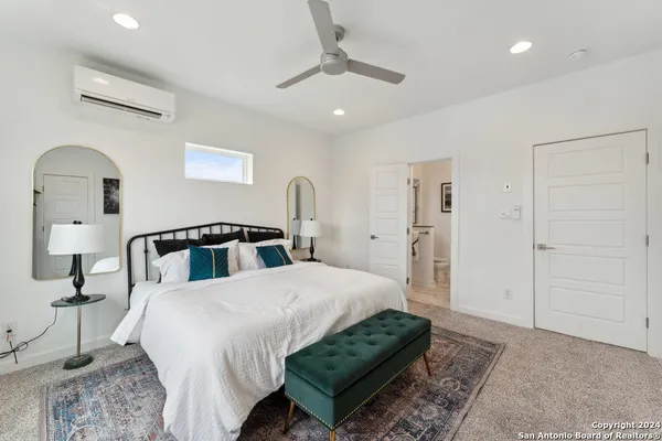 a spacious bedroom with a bed a chandelier and a dresser