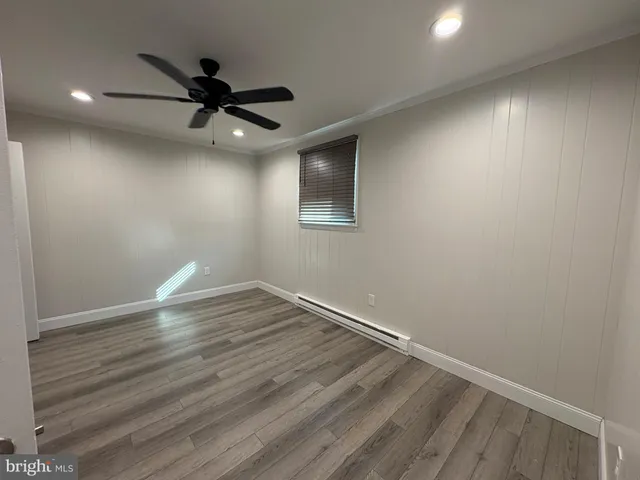 a view of an empty room with wooden floor and a ceiling fan