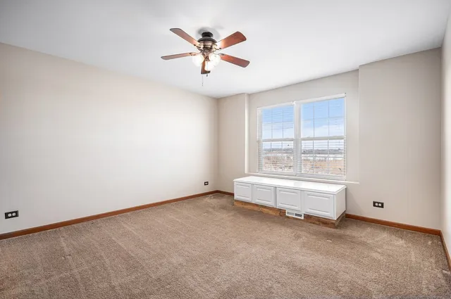 an empty room with chandelier fan and windows