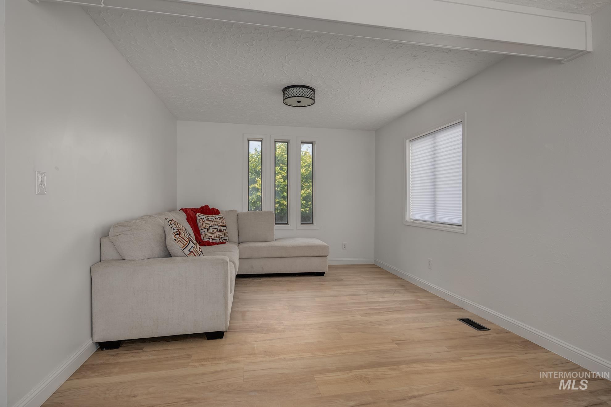 61 Southwest 4th Street Ontario, OR 97914 - Photo 8 of 42 Spacious interior featuring wood-finish flooring, white walls, and a recessed ceiling beam