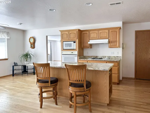 a kitchen with stainless steel appliances granite countertop a dining table chairs and a refrigerator