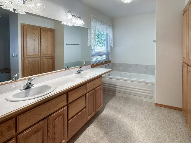 a bathroom with a double vanity sink a large mirror and a bathtub