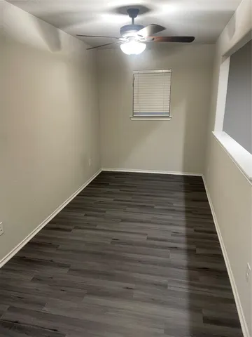 a view of an empty room with wooden floor and a chandelier fan