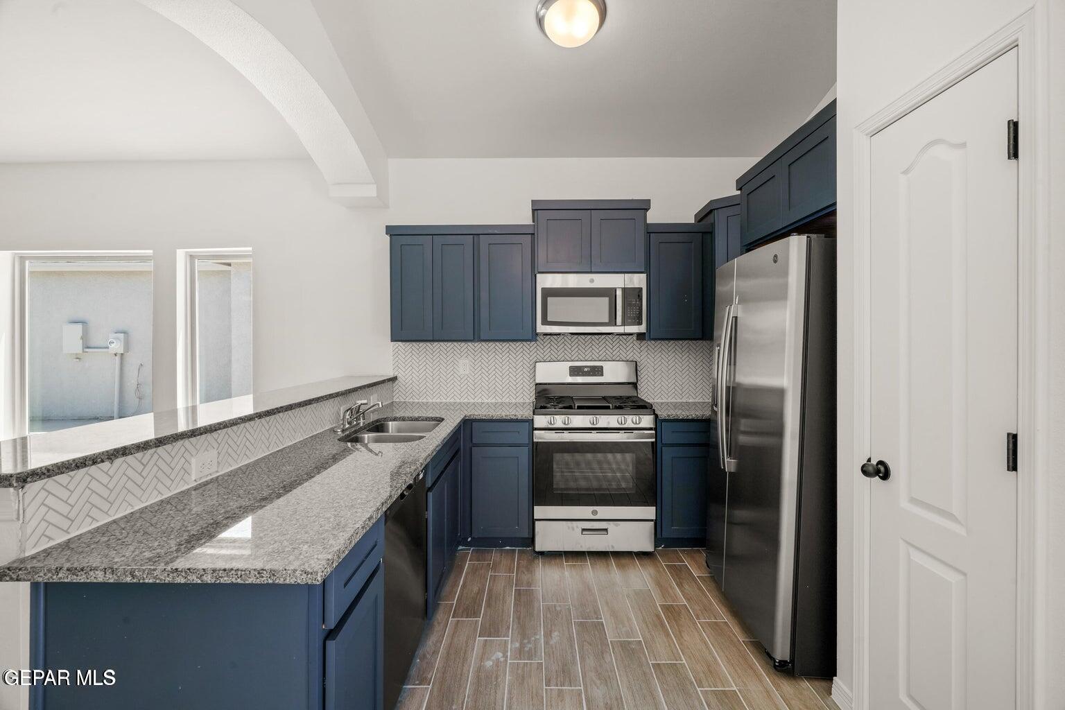13090 Beccles Street El Paso, TX 79928 - Photo 7 of 23 a kitchen with kitchen island granite countertop stainless steel appliances and wooden cabinets