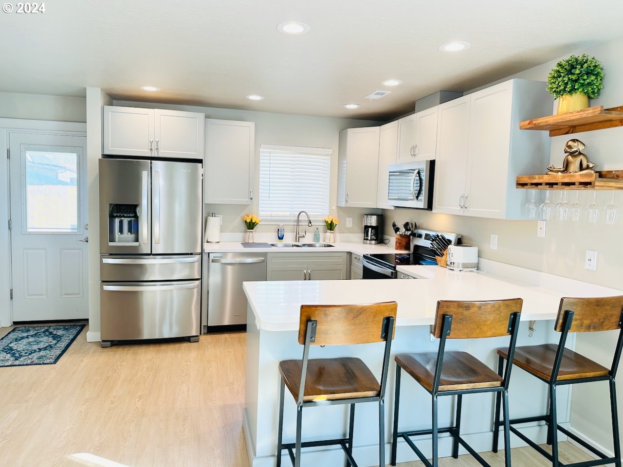 6470 Main Street Springfield, OR 97478 - Photo 8 of 35 a kitchen with stainless steel appliances a refrigerator a stove a sink and a dining table with wooden floor