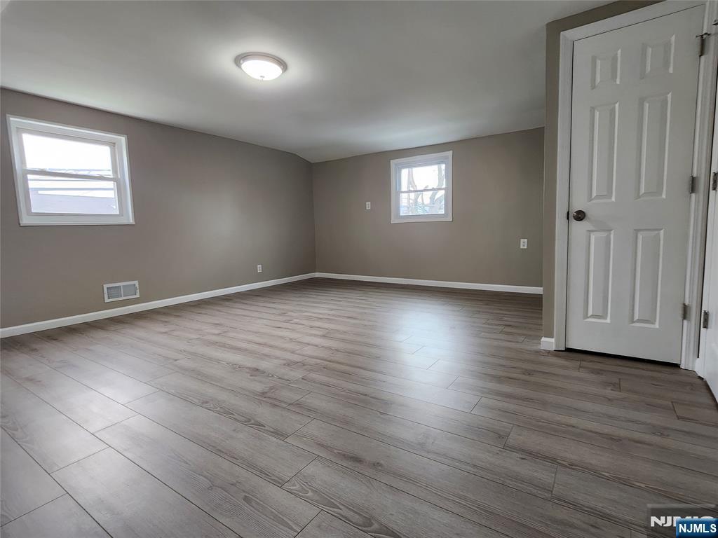 111 Church Street Lodi, NJ 07644 - Photo 11 of 21 an empty room with wooden floor and windows
