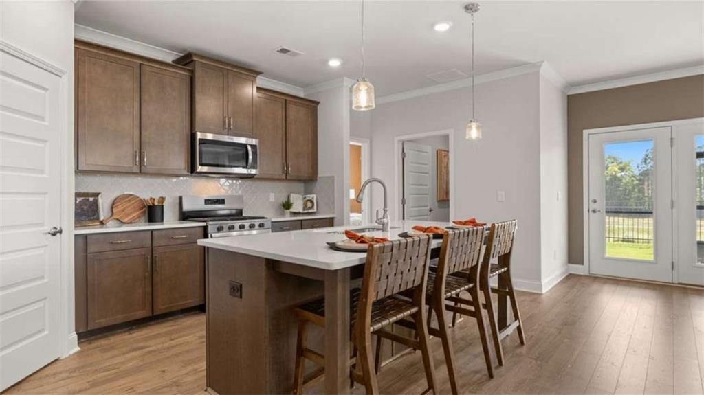636 Parnassus Road Locust Grove, GA 30248 - Photo 15 of 44 a kitchen with stainless steel appliances kitchen island granite countertop a sink a stove a dining table and chairs with wooden floor
