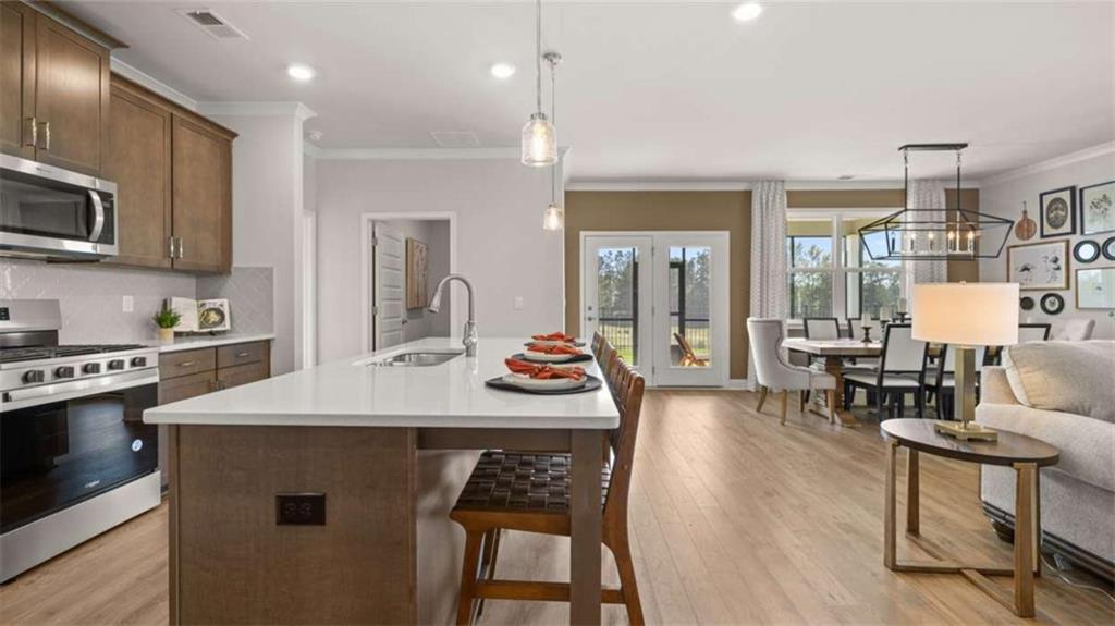 636 Parnassus Road Locust Grove, GA 30248 - Photo 21 of 44 a kitchen with stainless steel appliances granite countertop a stove a sink dishwasher a oven a dining table and chairs with wooden floor