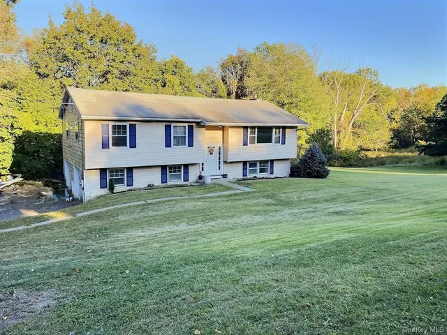 a view of a house with a big yard and large trees