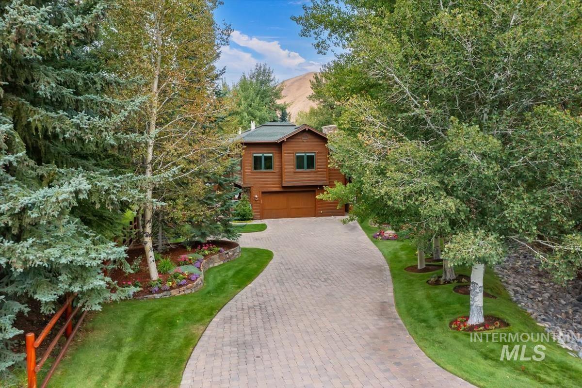 106 Hidden Hollow Road Hailey, ID 83333 - Photo 1 of 49 Wood-sided property with an attached garage, paver driveway, manicured lawn, and mature trees