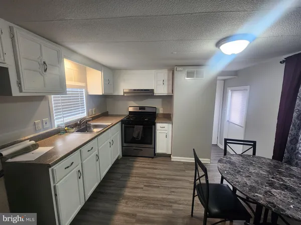 a kitchen with stainless steel appliances granite countertop a kitchen island hardwood floor sink stove dining table and chairs