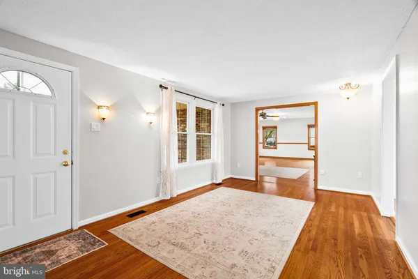 a living room with furniture a wooden floor and kitchen view