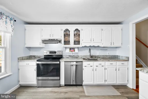 a kitchen with stainless steel appliances granite countertop a stove and white cabinets