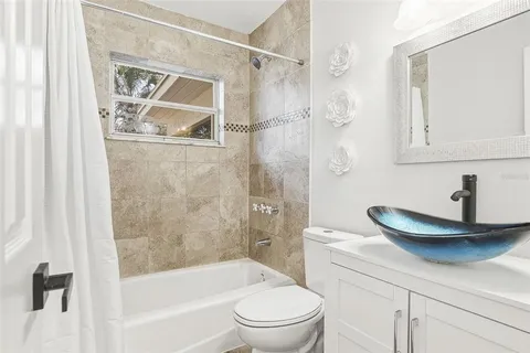 a bathroom with a granite countertop bathtub shower sink vanity and toilet