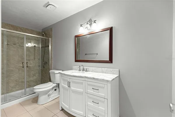 a bathroom with a granite countertop sink a toilet and shower