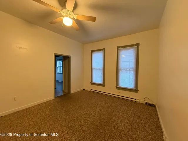 a view of an empty room with window and a ceiling fan