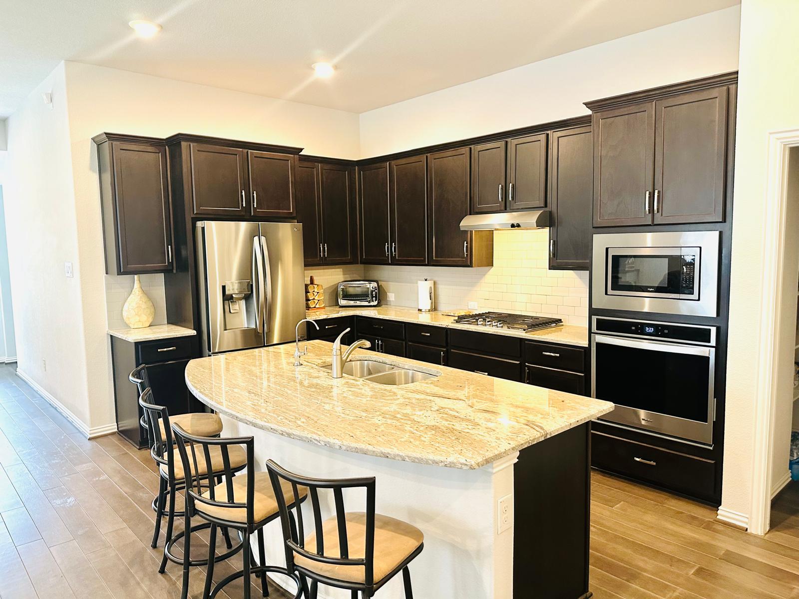 862 Leadtree Loop Buda, TX 78610 - Photo 14 of 40 a kitchen with stainless steel appliances wooden floor dining table and chairs