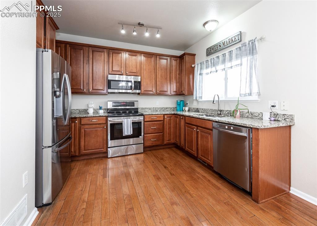 7751 Tompkins Road Peyton, CO 80831 - Photo 3 of 26 a kitchen with stainless steel appliances granite countertop wooden cabinets a sink dishwasher a stove and a refrigerator with wooden floor