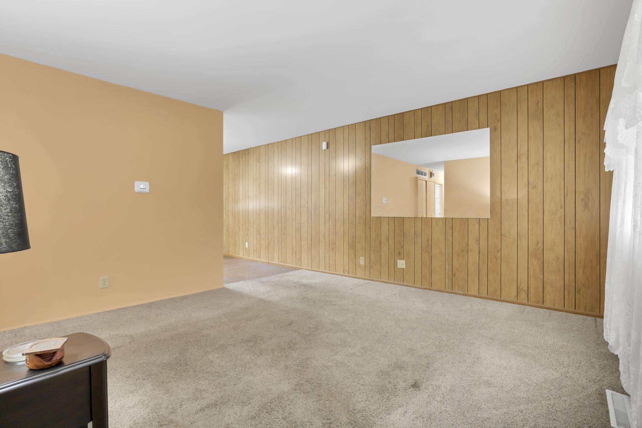 3882 Glenfield Road Columbus, OH 43232 - Photo 7 of 29 Spacious room featuring light-colored carpeting and a contrasting accent wall with vertical wood paneling
