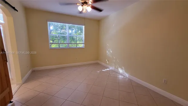 en empty room with windows and chandelier fan
