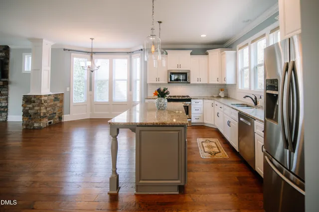 a kitchen with stainless steel appliances granite countertop a refrigerator a stove top oven a sink dishwasher and wooden floor