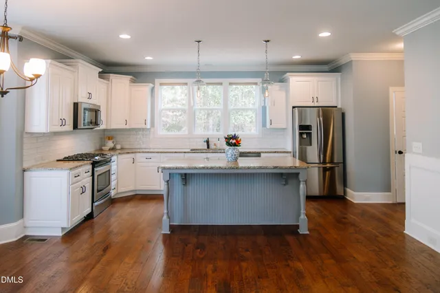 a kitchen with kitchen island granite countertop a sink cabinets and stainless steel appliances