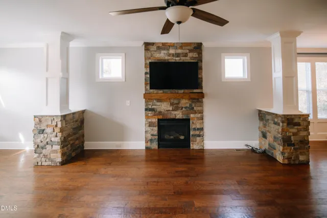 an empty room with furniture wooden floor fireplace and windows
