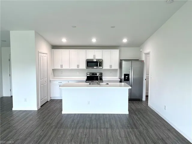 a kitchen with stainless steel appliances granite countertop a stove a refrigerator a sink a microwave oven with wooden floor and cabinets