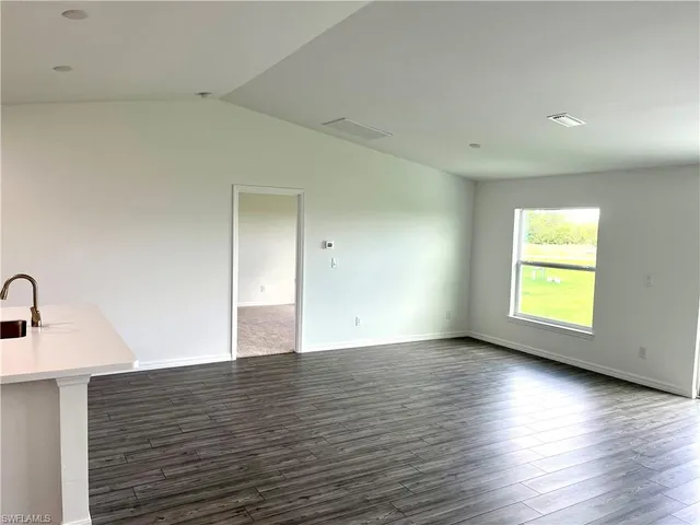 a view of an empty room with window and wooden floor