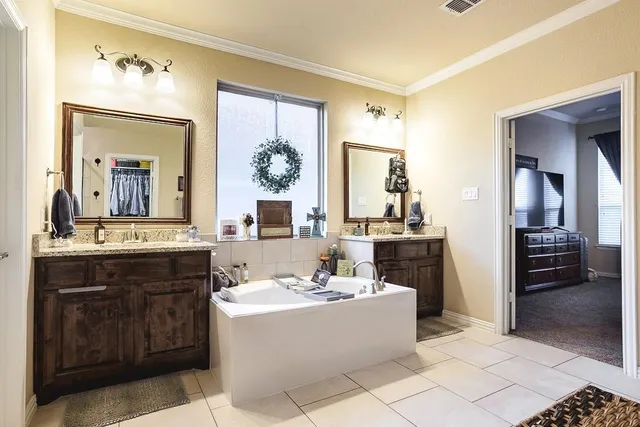 a bathroom with a tub a double vanity sink and a mirror