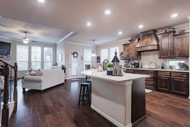 a kitchen with kitchen island granite countertop a sink cabinets and wooden floor