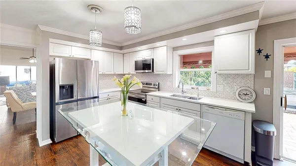 a kitchen with stainless steel appliances granite countertop a sink a stove a refrigerator with a dining table and chairs