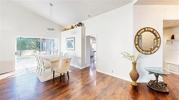 a dining room with wooden floor a glass table and chairs