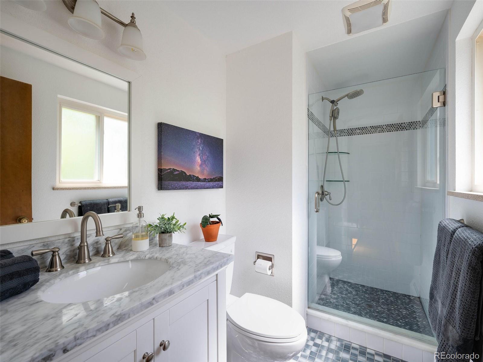 1826 Smith Road Golden, CO 80401 - Photo 20 of 35 a bathroom with a granite countertop sink a mirror a toilet and shower