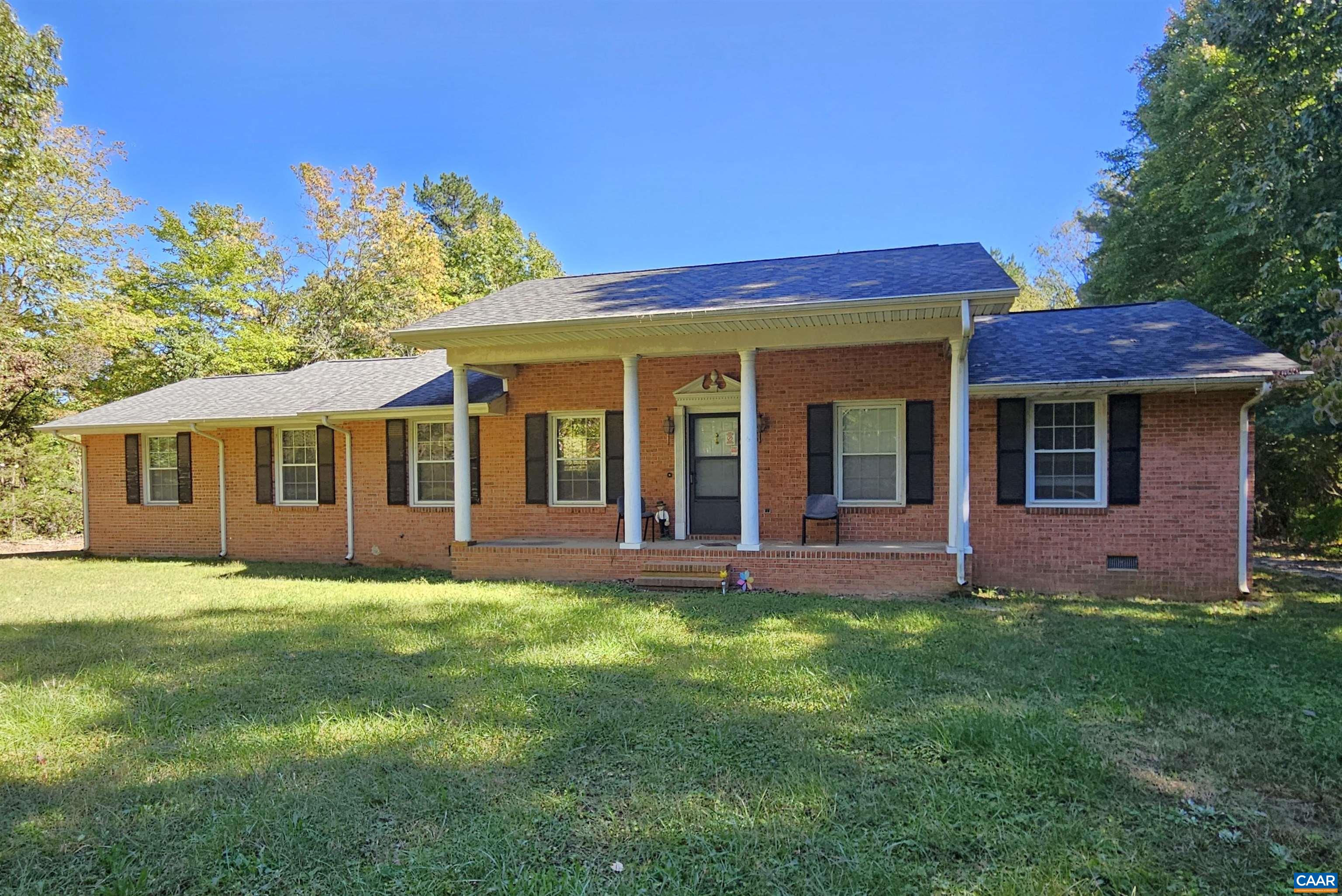 a view of a yard in front of a brick house with large windows