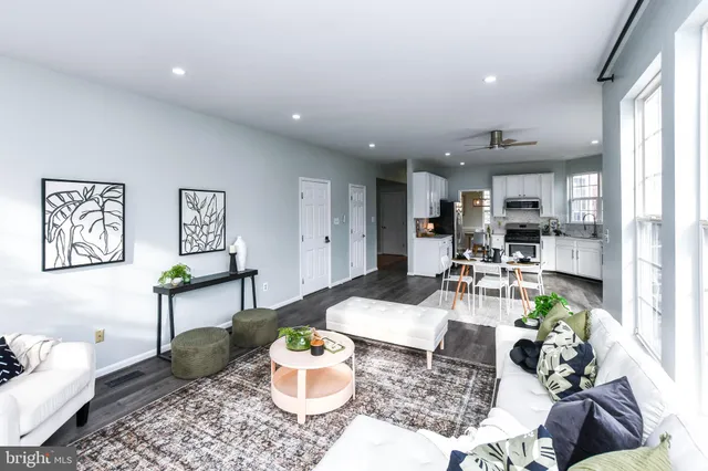 a living room with stainless steel appliances furniture wooden floor and a large window