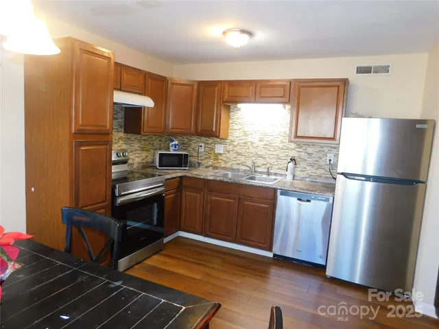 a kitchen with granite countertop a refrigerator stove and sink