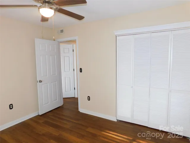 an empty room with wooden floor closet and windows