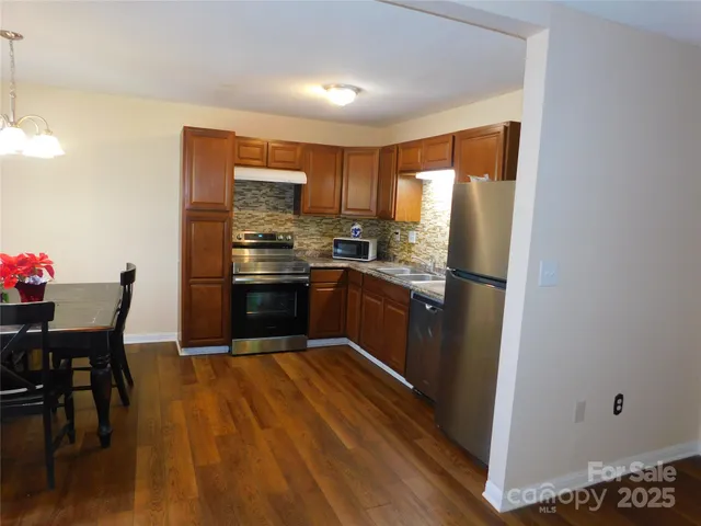 a kitchen with stainless steel appliances granite countertop a stove refrigerator and a chair